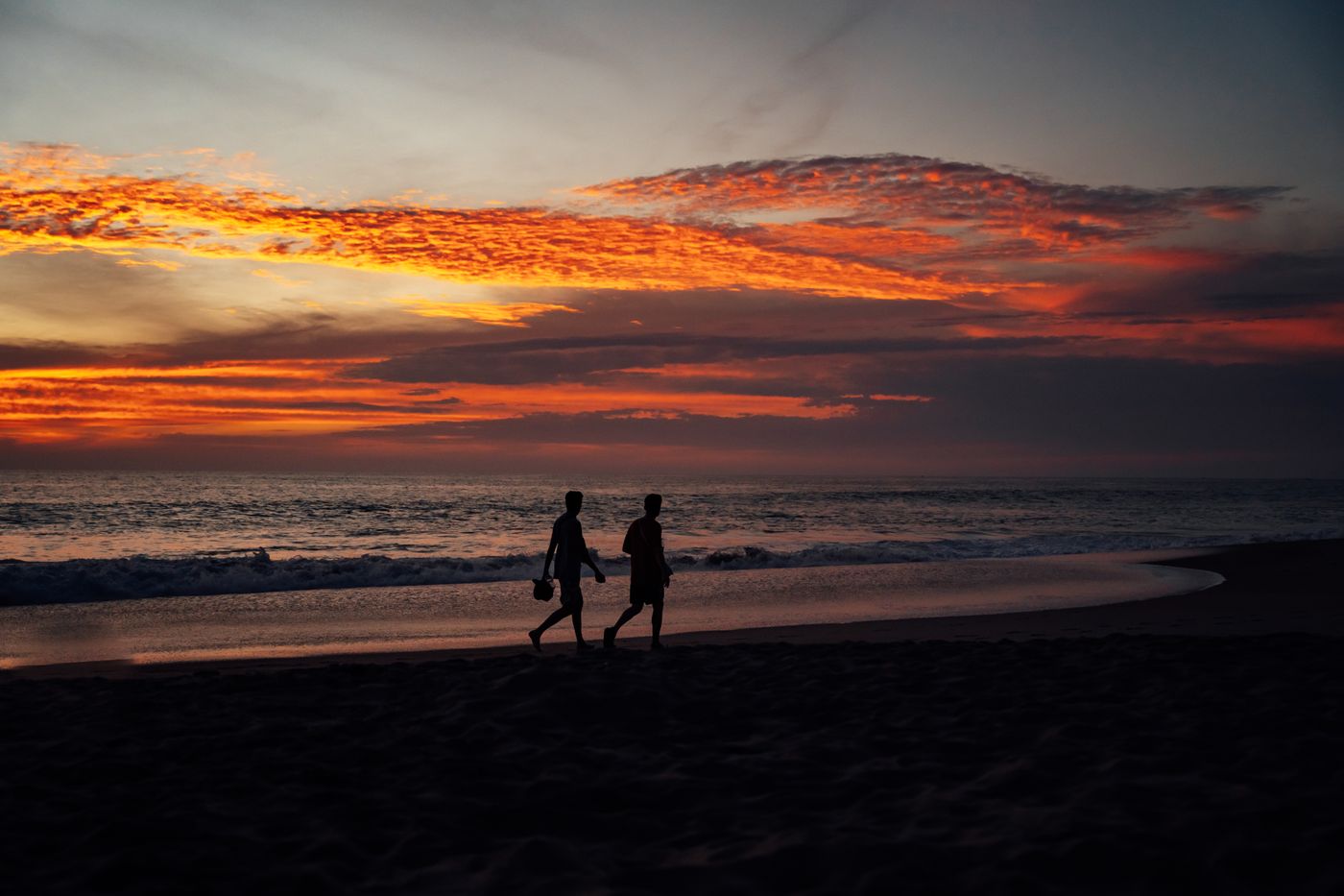 Dos personas caminan al atardecer por la playa de Puerto Escondido