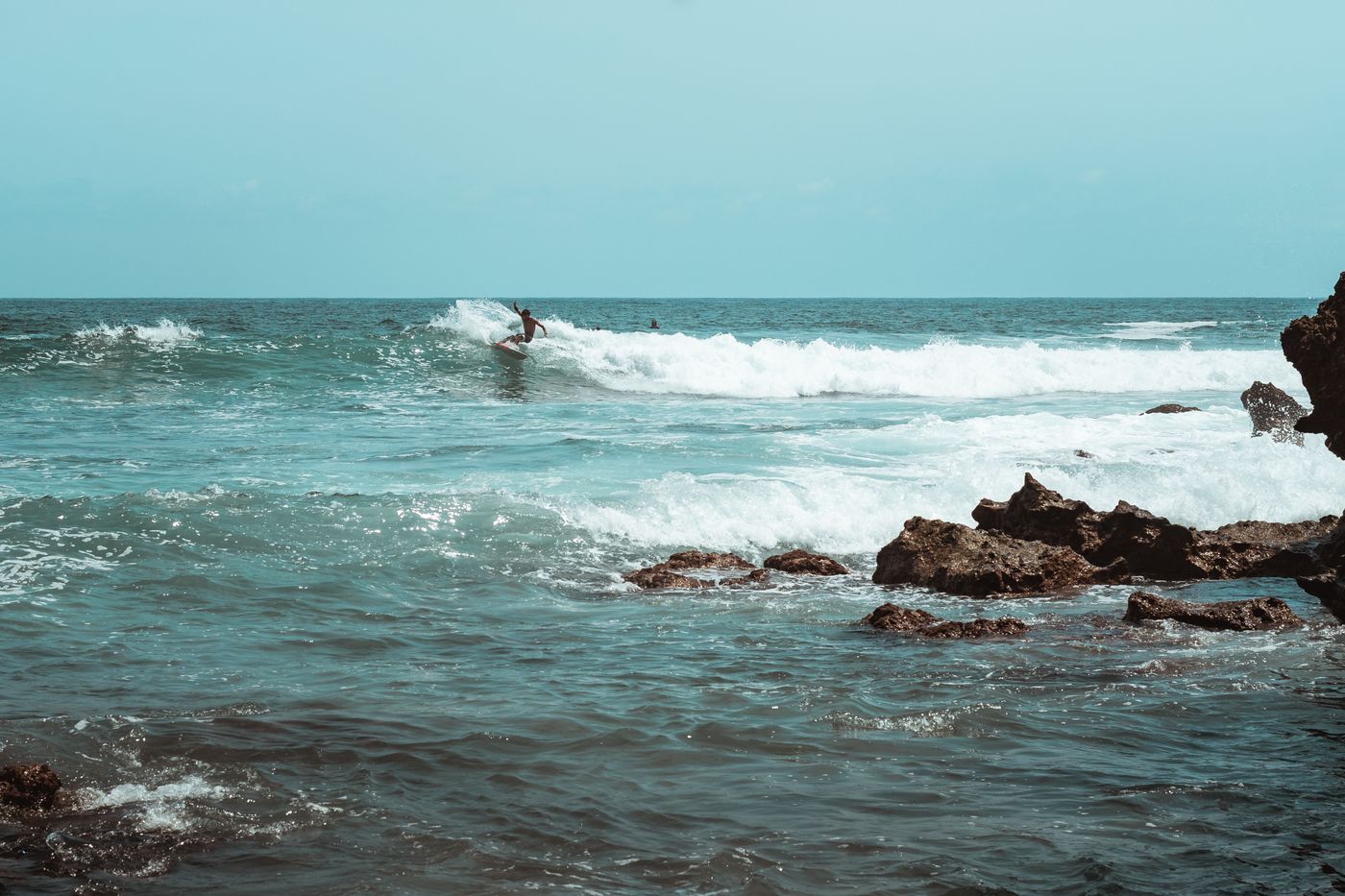Surfista toma una ola en la costa rocosa de Puerto Escondido